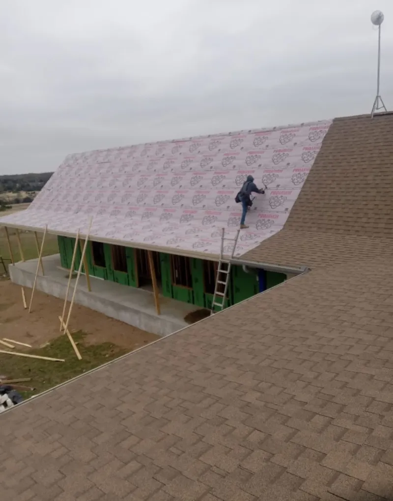 Worker preparing underlayment for a metal roof installation in Branford